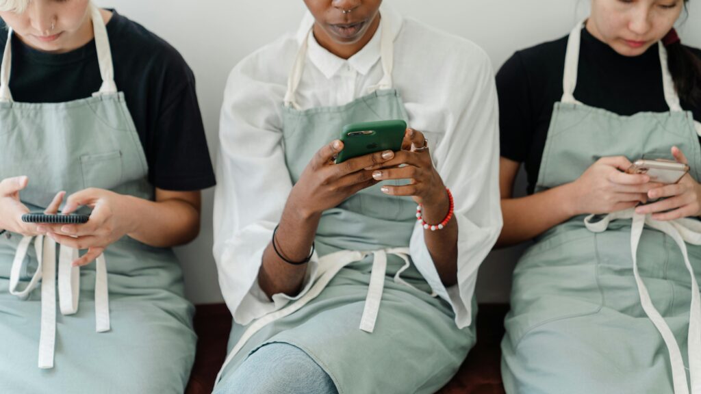 The image shows three women in aprons, looking down at the their phones. The implication is they're using Social Media.