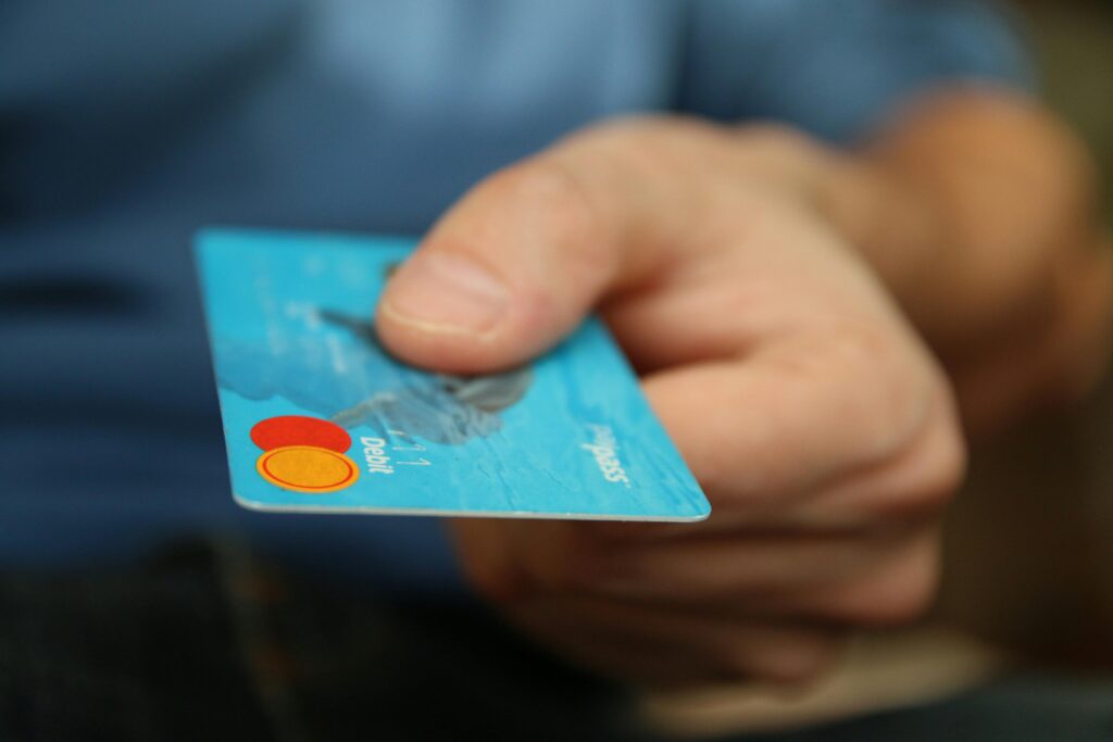 The image shows a close up of a hand giving a credit card.