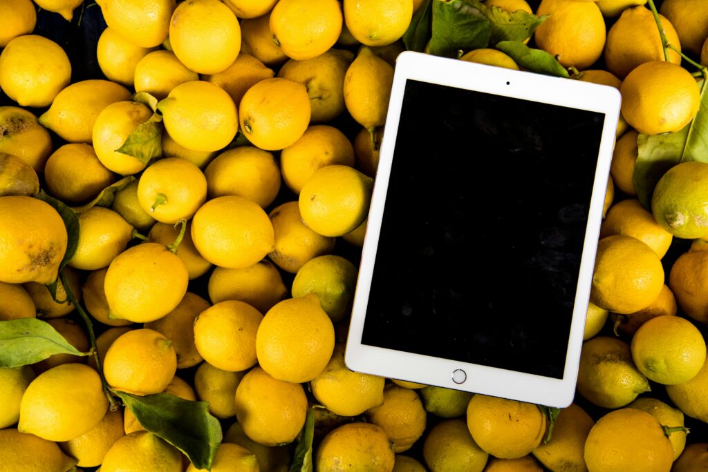 The image shows a tablet on a pile of yellow fruit, likely lemons.